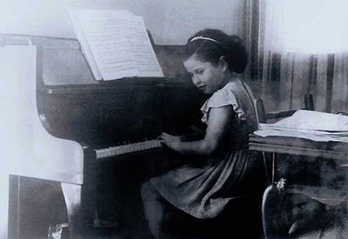 Tsippi as a child next to the piano
